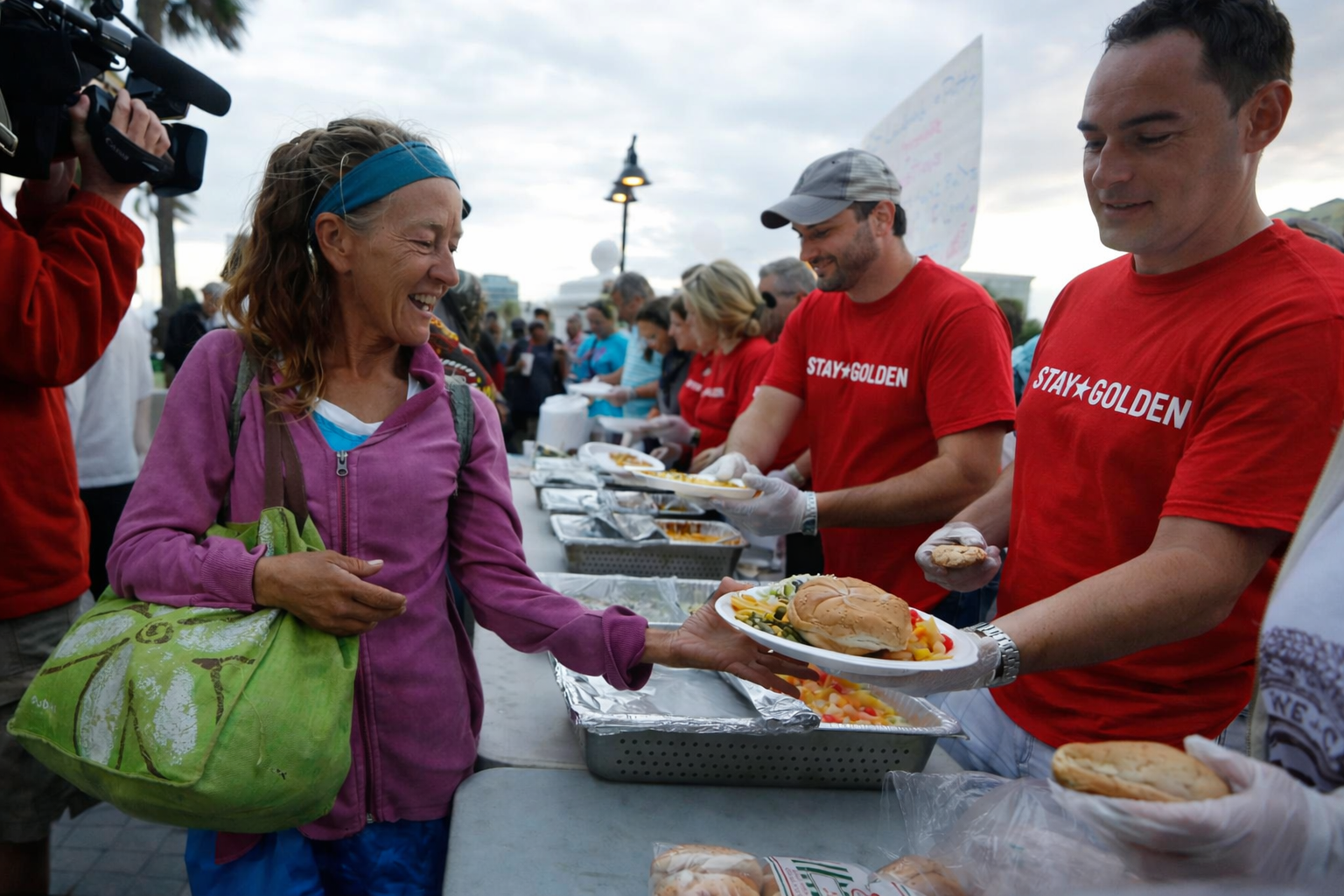 A Stay Golden volunteer hands a hot meal to a neighbor in need