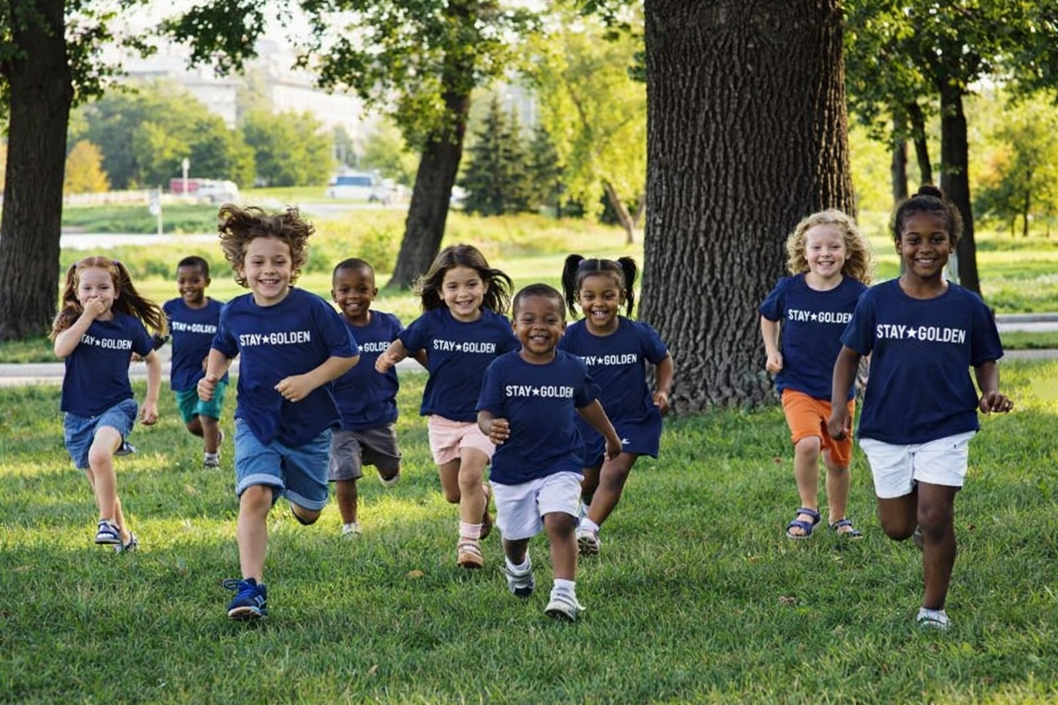 Kids in Stay Golden shirts running joyfully through the park